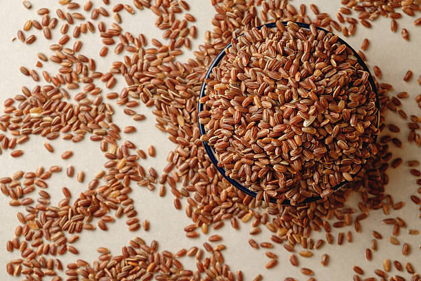 istock Organic brown rice heaped in a bowl with scattered grains around it 2217370480