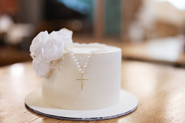 Stock photo shows a stunning white wedding cake with smooth fondant icing stands elegantly on a beach, capturing a romantic seaside celebration. Adorned with delicate bride and bridgegroom toppers, this cake symbolizes love and commitment