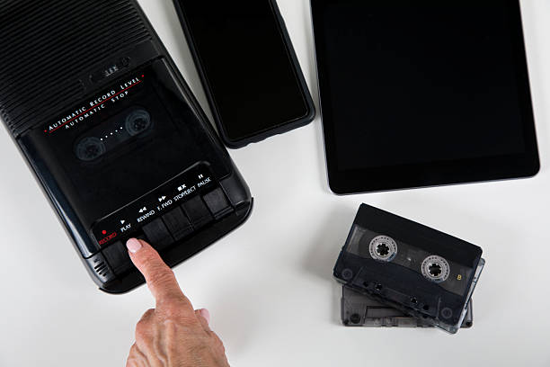 Analog audio cassette player with finger pressing play button, with modern tablet and mobile phone along side.