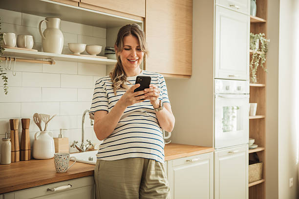 istock Mature pregnant woman using mobile phone at kitchen 2217374641