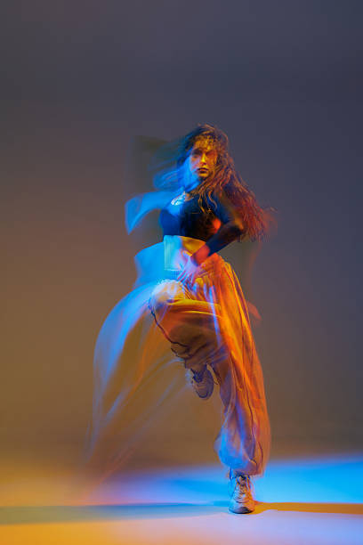 istock Stylized jazz-funk dancer captured mid-motion with vivid neon lighting, dynamic movement trails, and expressive pose in urban studio setting, showcasing rhythm and energy. 2217375950