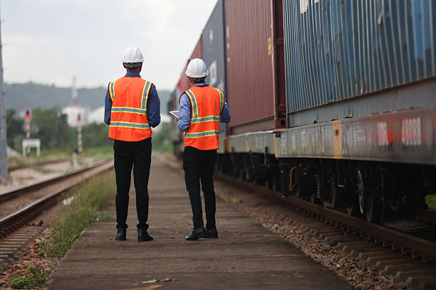 istock Two Indian logistic staff with safety jacket and PPE check container on rail transportation ,World wide logistic, The container cargo shipment by rail transportation , Logistic manager and staff working check container on rail way 2217376189