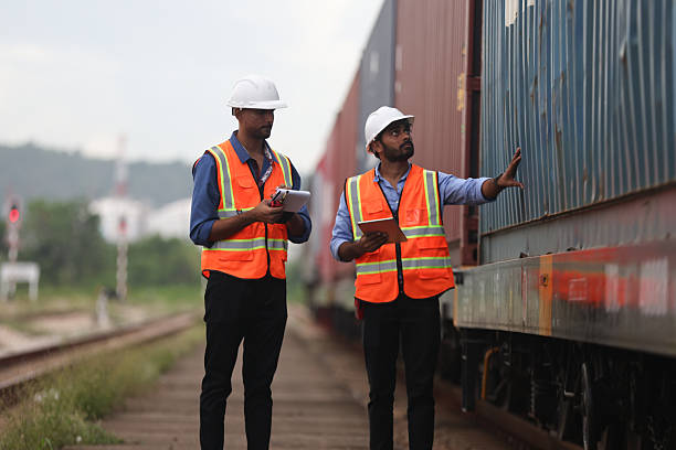 istock Two Indian logistic staff with safety jacket and PPE check container on rail transportation ,World wide logistic, The container cargo shipment by rail transportation , Logistic manager and staff working check container on rail way 2217376190