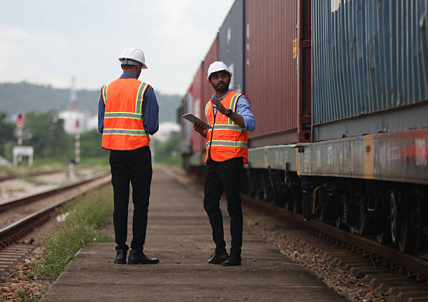 istock Two Indian logistic staff with safety jacket and PPE check container on rail transportation ,World wide logistic, The container cargo shipment by rail transportation , Logistic manager and staff working check container on rail way 2217376191