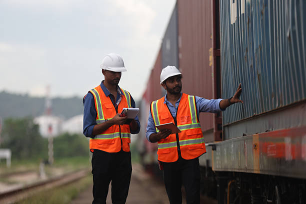istock Two Indian logistic staff with safety jacket and PPE check container on rail transportation ,World wide logistic, The container cargo shipment by rail transportation , Logistic manager and staff working check container on rail way 2217376195