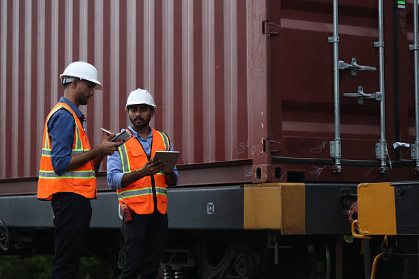 istock Two Indian logistic staff with safety jacket and PPE check container on rail transportation ,World wide logistic, The container cargo shipment by rail transportation , Logistic manager and staff working check container on rail way 2217376206