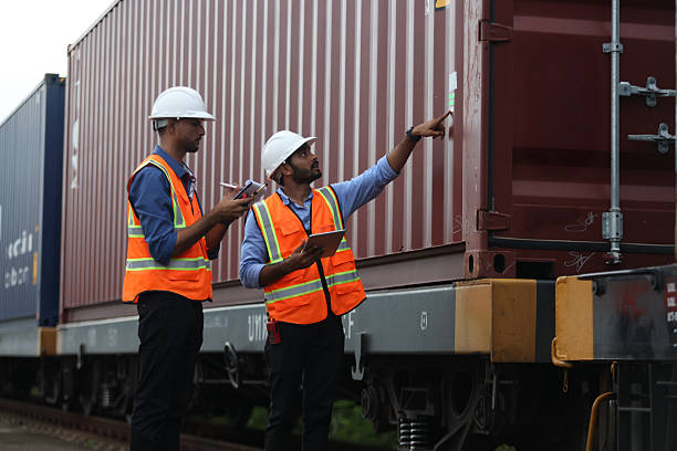 istock Two Indian logistic staff with safety jacket and PPE check container on rail transportation ,World wide logistic, The container cargo shipment by rail transportation , Logistic manager and staff working check container on rail way 2217376212