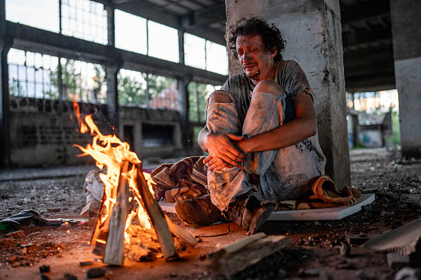 istock Man Warming Hands by a Fire in Abandoned Industrial Building 2217377005