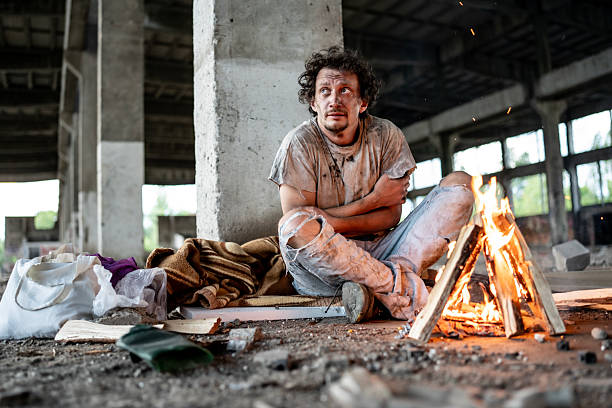 istock Homeless Man Keeping Warm By Fire in Abandoned Urban Building 2217377036