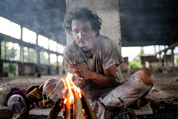 istock Man Sitting by Fire in Abandoned Building Looking Contemplative 2217377069