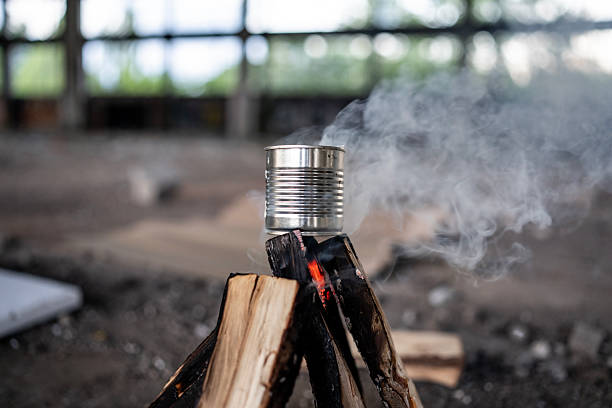 Tin can emitting smoke while heated on a makeshift fire in an urban setting, depicting survival concepts.