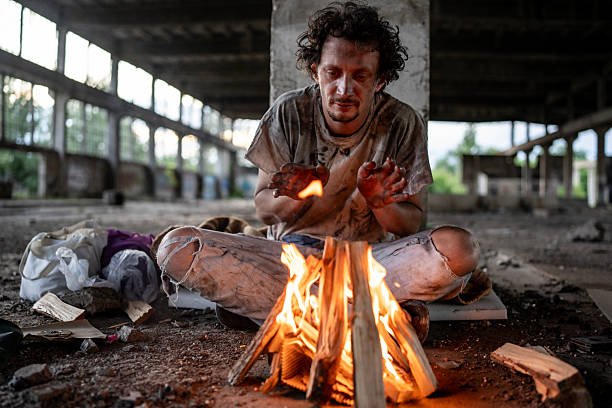 istock Homeless Man Warming Hands by Fire in Abandoned Building 2217377104