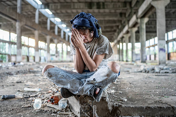 istock Tired Wanderer Sitting in an Abandoned Industrial Warehouse Amidst Disarray 2217377286