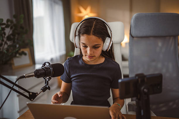 istock school girl use tripod camera to record while play games on laptop 2217379719