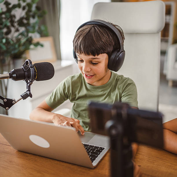 istock school boy use tripod camera to record while play games on laptop 2217379720