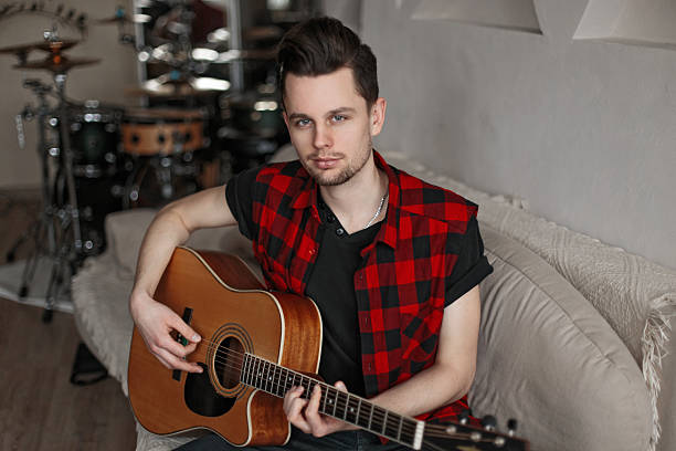 istock Handsome young man in shirt holding guitar 2217379729