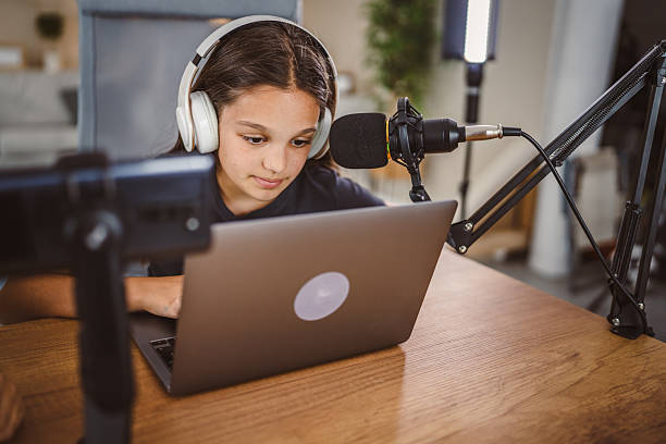 istock school girl use tripod camera to record while play games on laptop 2217380116