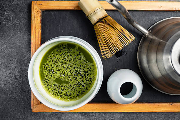 Matcha green tea and a traditional bamboo brush whisk or chasen on a black table. Accessories for making matcha green tea. Top view