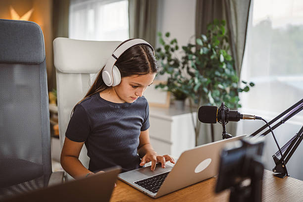 istock school girl use tripod camera to record while play games on laptop 2217380975