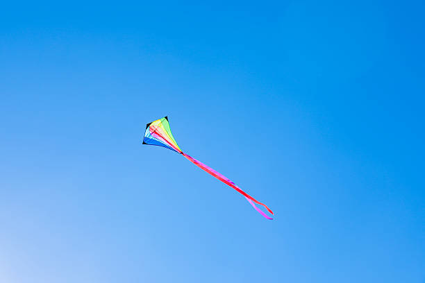 istock One colorful kite flying in blue sky on sunny day 2217385755