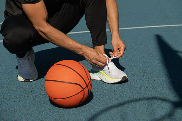 istock Basketball player tying running shoes shoelace before training. 2217388833