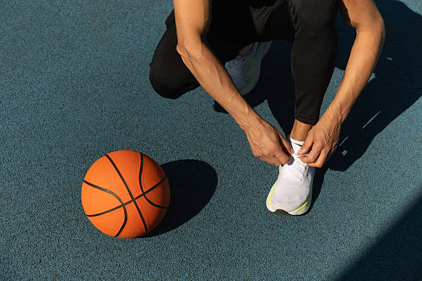 istock Basketball player tying running shoes shoelace before training. 2217388838