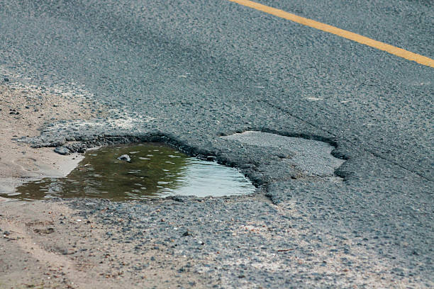 istock Old asphalt road with dangerously damaged asphalt that has potholes dangerous for the transit of motor vehicles 2217390063