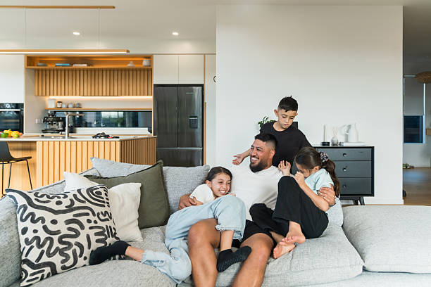 Maori family with three children, father being playful with children laughing with big smile on their faces, spending leisure time with family concept.