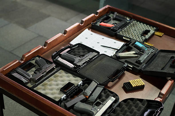 Collection of various handguns in protective cases displayed on table photographed from above showing different designs and calibers