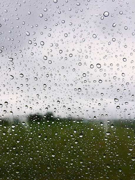 Close-up of water droplets on a glass window with a blurred view of the lush Icelandic countryside in the background. Shot on iPhone.
