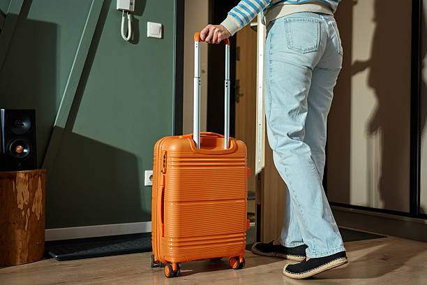 istock Person leaving home with orange suitcase 2217411498