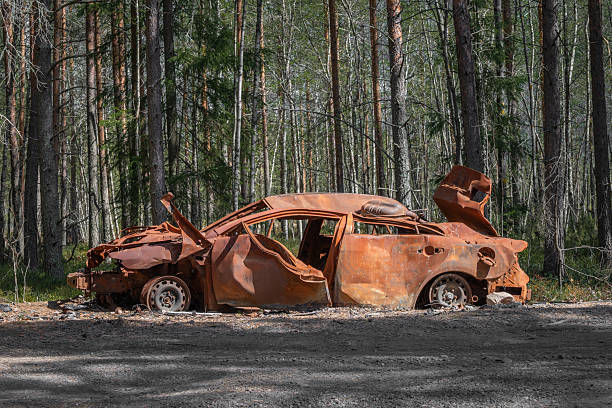 istock An abandoned, wrecked, extremely rusty burnt car on the side of a forest road. 2217412241