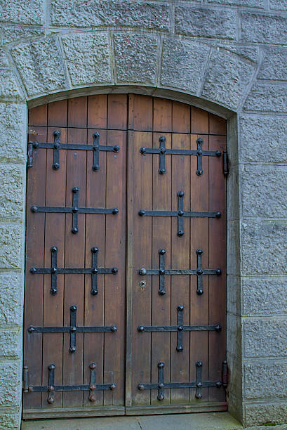 istock A weathered wooden door with robust iron hardware stands within a sturdy stone archway. 2217412383
