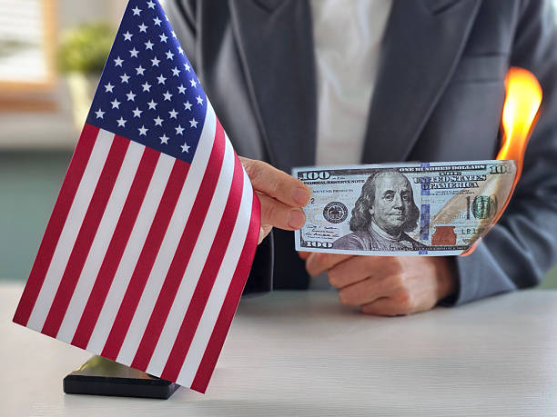 istock Holding a hundred dollar bill near a small American flag in modern office setting 2217414600