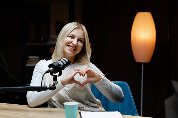istock Smiling woman making heart shape with hands during podcast recording 2217415116