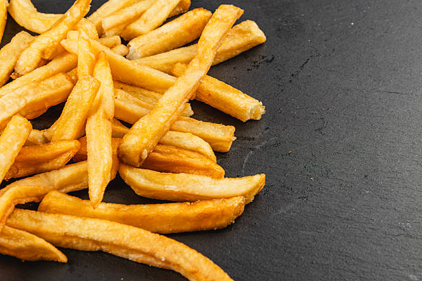 istock Crispy French fries piled on a dark surface 2217417906
