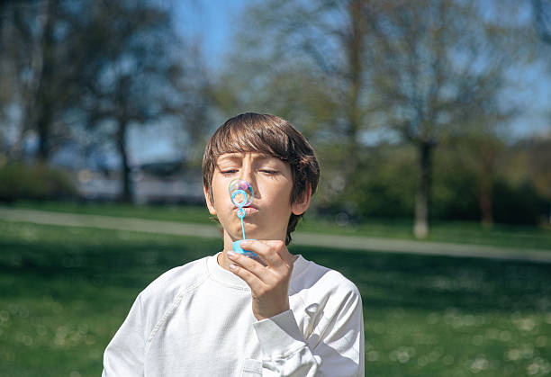 Boy and girl playing  in a park and blowing bubbles