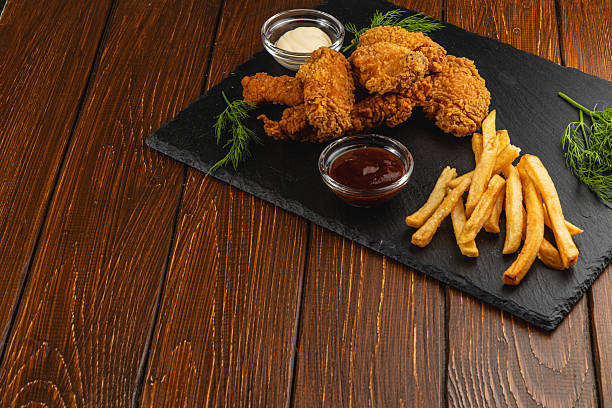 Crispy fried chicken with fries and dips on slate