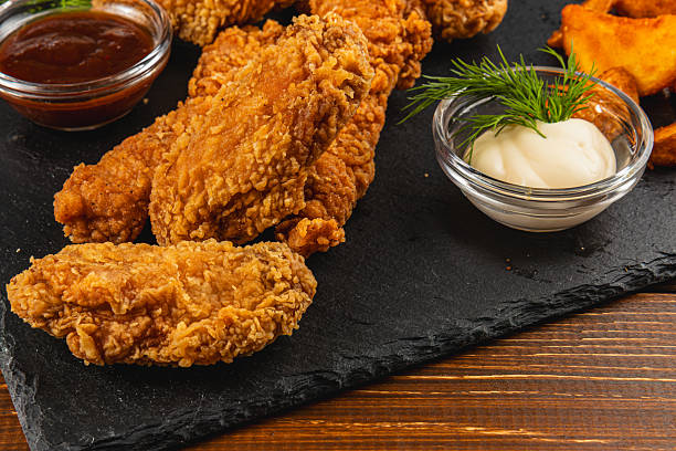 istock Delicious fried chicken served with sauces on rustic board 2217418867