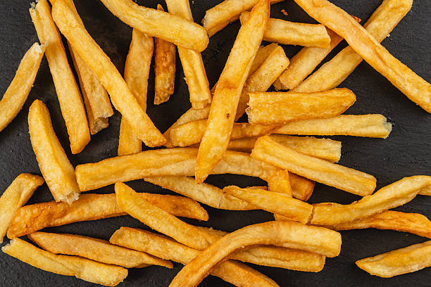 istock Crispy golden fries spread out on a dark surface 2217419794