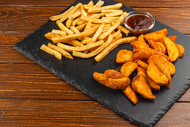 Various types of fried potatoes served on a black slate board