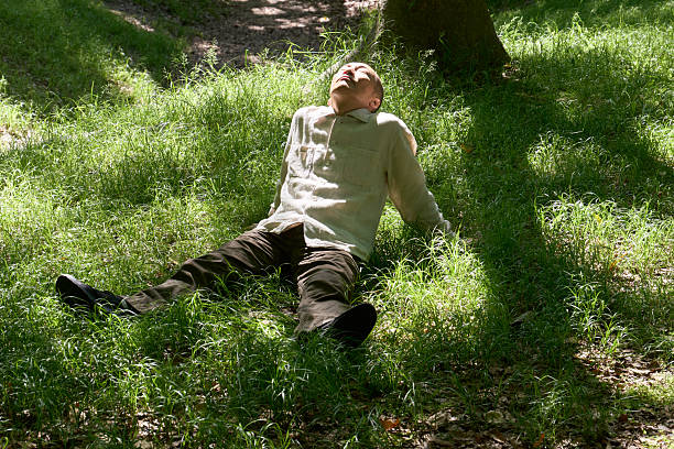 istock A man relaxes on the grass with the sun shining through the trees 2217420550