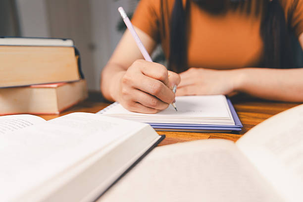 istock woman sitting at desk working on laptop taking notes in notebook, female studying online, watching webinar using computer, writing check list. Remote college school education, e learning concept. 2217420791