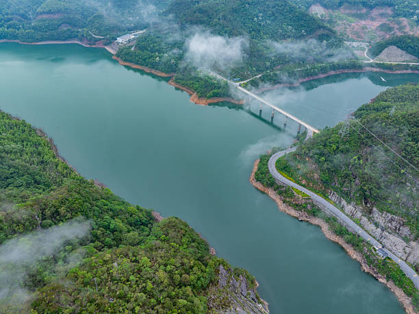 istock Winding mountain road beside green forest lake 2217421629