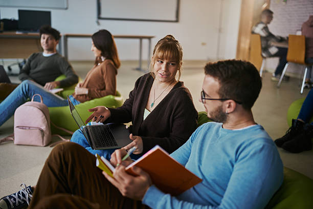 istock Couple of students talking while e-learning over laptop at casual classroom. 2217423155