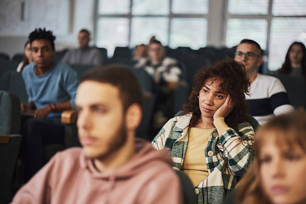 Bored black college student attending a class in amphitheater.