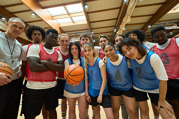 istock Diverse high school basketball team posing with coach and ball 2217423267