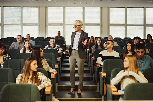 istock Happy senior professor talking to her students on a class at lecture hall. 2217423323