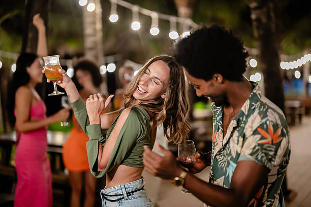 istock Young adults dancing and enjoying drinks at an outdoor night party under string lights, filled with laughter, music, and festive vibes. 2217423409