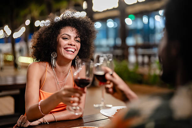 istock Romantic couple enjoying an intimate dinner under string lights at night, holding hands and smiling while dining outdoors at a tropical beachside restaurant. 2217423516